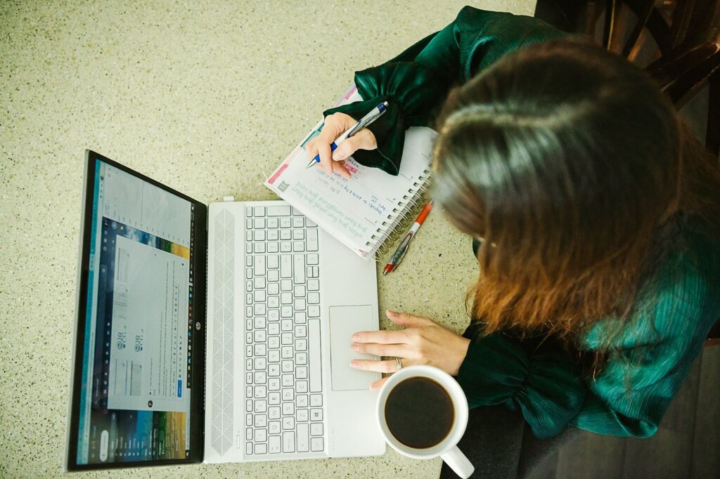 Overtop photo of a digital marketing expert working on laptop with coffee in hand. 